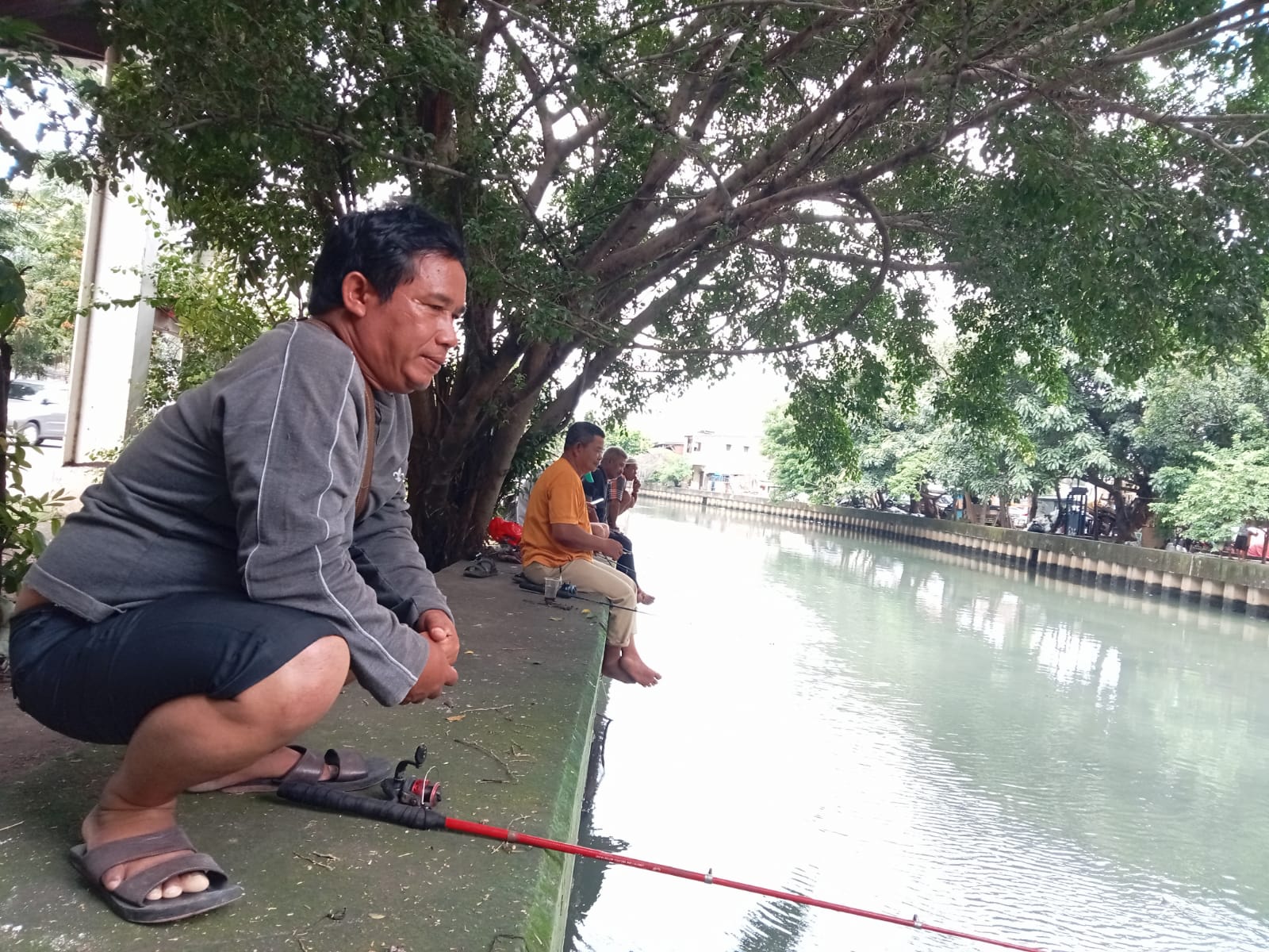 Didik (50) dan beberapa warga bantaran Sungai Angke Teluk Gong, Penjaringan Jakarta Utara tengah memancing dalam mengisi akhir pekan, ikan lele yang di pancing Didik akan dia bawa ke keluarganya untuk dijadikan lauk (DP.Sari/Prohealth)